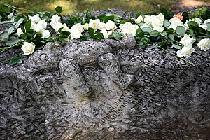Das Foto zeigt den Gedenkstein von Vitos Rheingau mit weißen Rosen